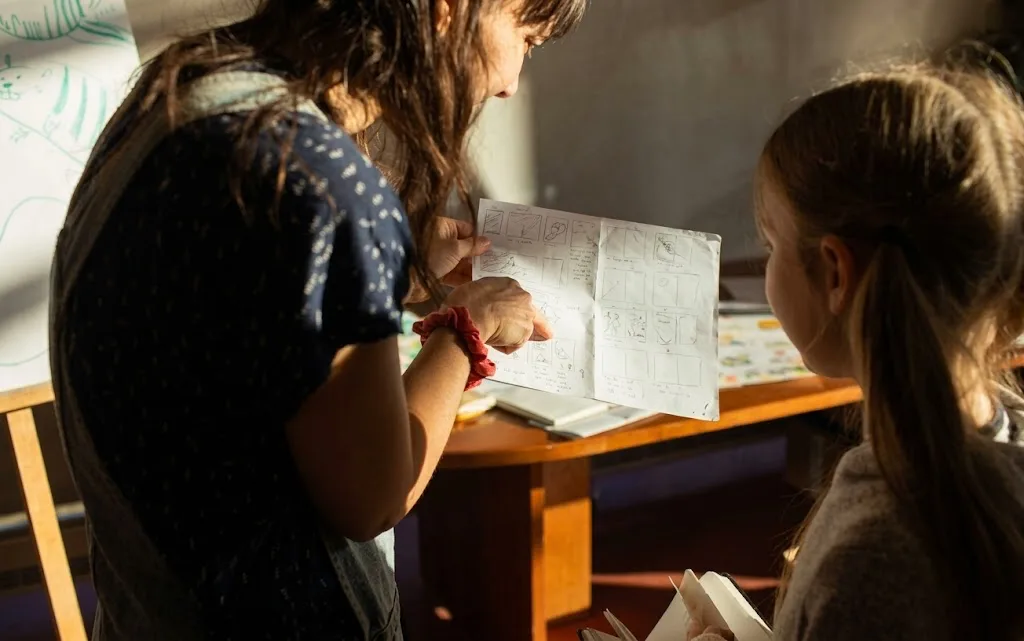 Educadora acompanhando uma aluna em uma atividade de desenho
